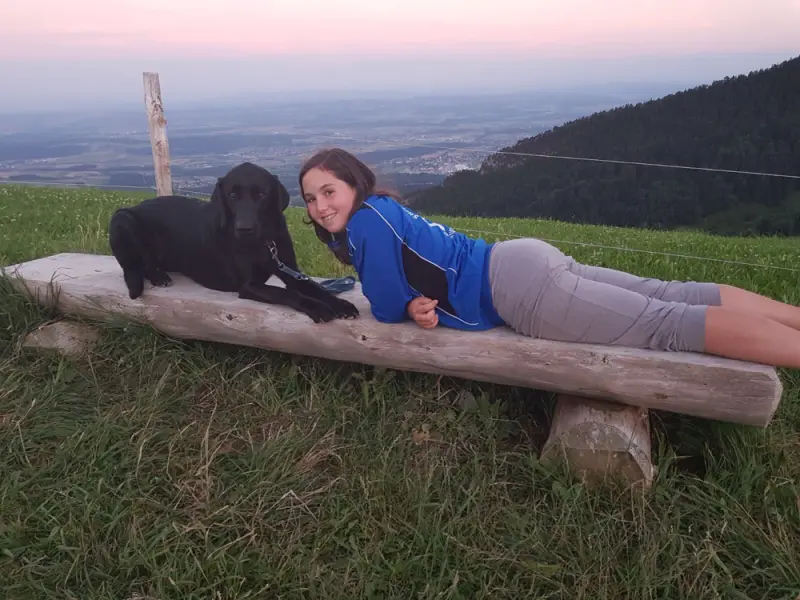Eine Frau, die mit einem Hund auf einem Baumstamm liegt. – Jugend und Hund Lager 2017 in Balmberg
