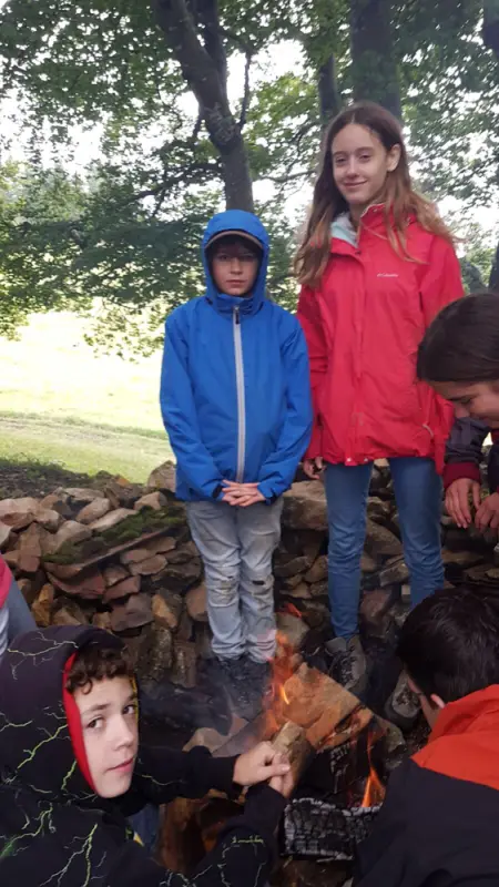 Eine Gruppe von Kindern, die um ein Feuer stehen. – Jugend und Hund Lager 2017 in Balmberg