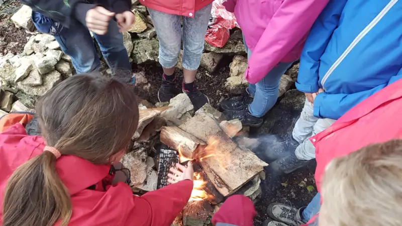 Eine Gruppe von Kindern, die um ein Feuer stehen. – Jugend und Hund Lager 2017 in Balmberg