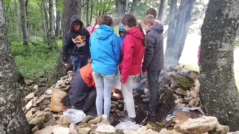 Eine Gruppe von Menschen, die um ein Feuer stehen. – Jugend und Hund Lager 2017 in Balmberg