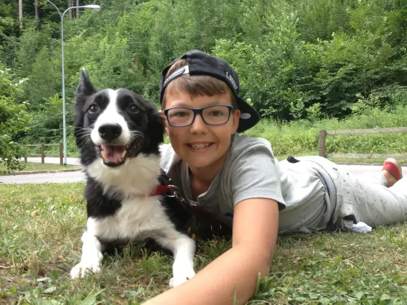 Ein junger Junge, der mit einem Hund auf dem Gras liegt. – Jugend und Hund Lager 2013 in Chur