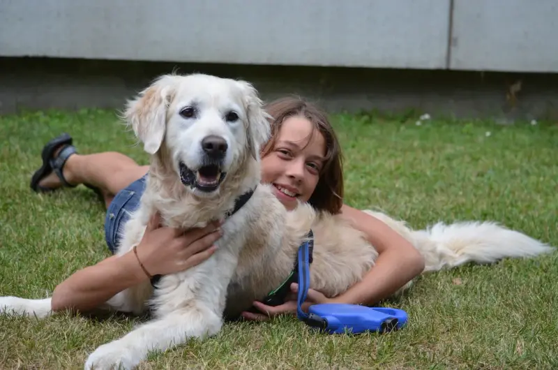 Eine Frau, die mit einem Hund auf dem Gras liegt. – Jugend und Hund Lager 2013 in Chur