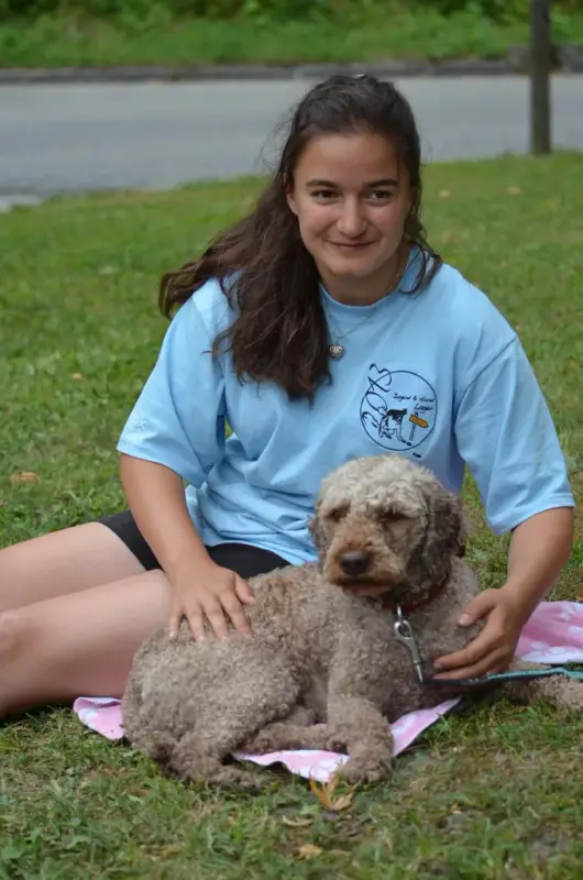 Ein Mädchen sitzt auf dem Gras mit einem Hund. – Jugend und Hund Lager 2013 in Chur