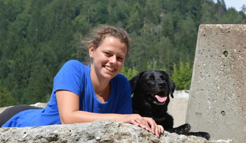Eine Frau, die mit einem Hund auf einem Felsen liegt. – Jugend und Hund Lager 2014 in Chur