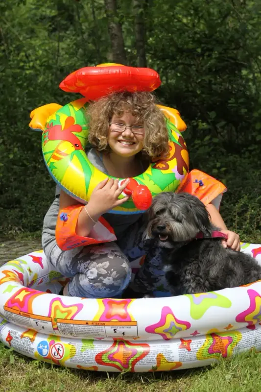 Ein kleines Mädchen sitzt in einem Pool mit ihrem Hund. – Jugend und Hund Lager 2014 in Chur