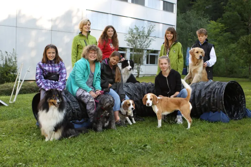 Eine Gruppe von Menschen, die auf dem Gras sitzen. – Jugend und Hund Lager 2014 in Chur