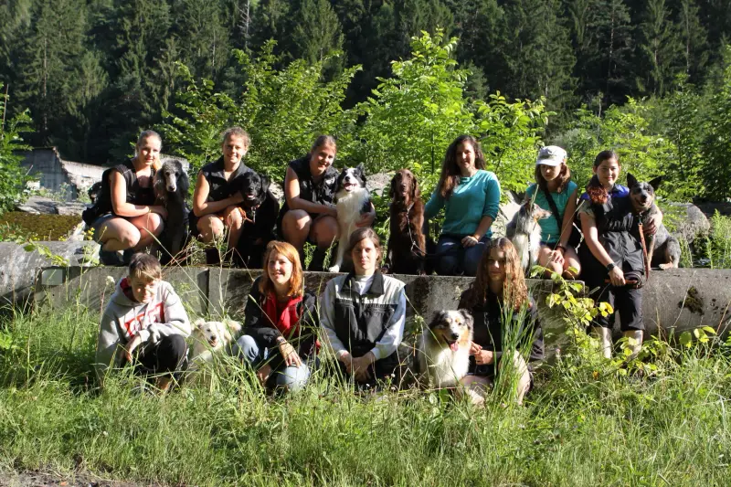 Eine Gruppe von Menschen, die auf einem Felsen auf einem Feld sitzen. – Jugend und Hund Lager 2014 in Chur