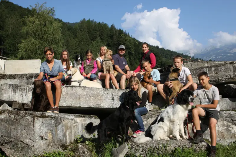 Eine Gruppe von Menschen, die auf einer Steinmauer sitzen. – Jugend und Hund Lager 2014 in Chur
