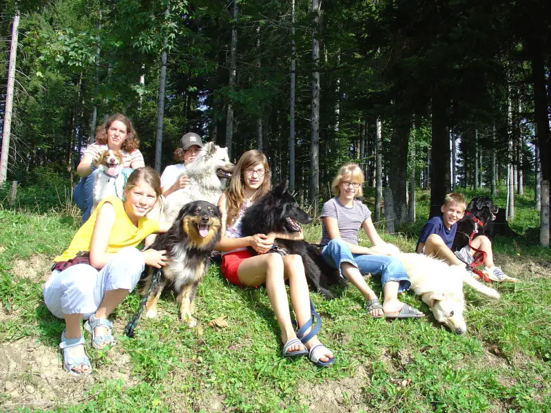 Eine Gruppe von Menschen, die auf einem Hügel mit einem Hund sitzen. – Jugend und Hund Lager 2005 in Ebnatkappel