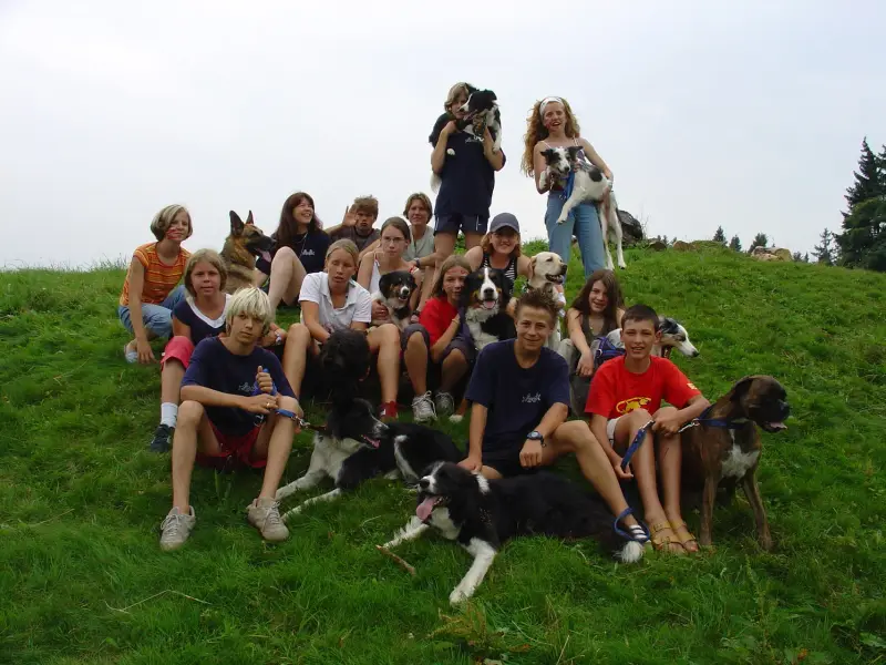 Eine Gruppe von Menschen, die auf einem Hügel mit einem Hund sitzen. – Jugend und Hund Lager 2005 in Ebnatkappel