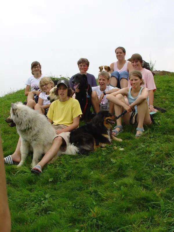 Eine Gruppe von Menschen, die auf einem Hügel mit einem Hund sitzen. – Jugend und Hund Lager 2005 in Ebnatkappel