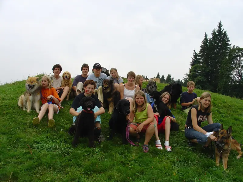 Eine Gruppe von Menschen, die mit ihren Hunden auf einem Hügel sitzen. – Jugend und Hund Lager 2005 in Ebnatkappel