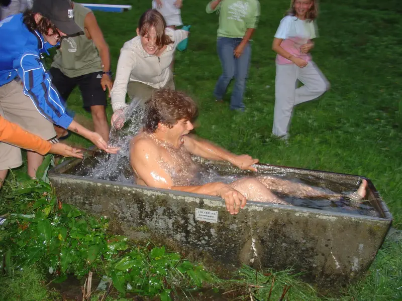 Ein Mann nimmt ein Bad in einer steinernen Badewanne. – Jugend und Hund Lager 2005 in Ebnatkappel