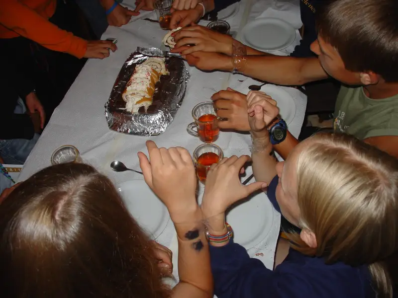 Eine Gruppe von Menschen, die um einen Tisch sitzen und Essen essen. – Jugend und Hund Lager 2005 in Ebnatkappel