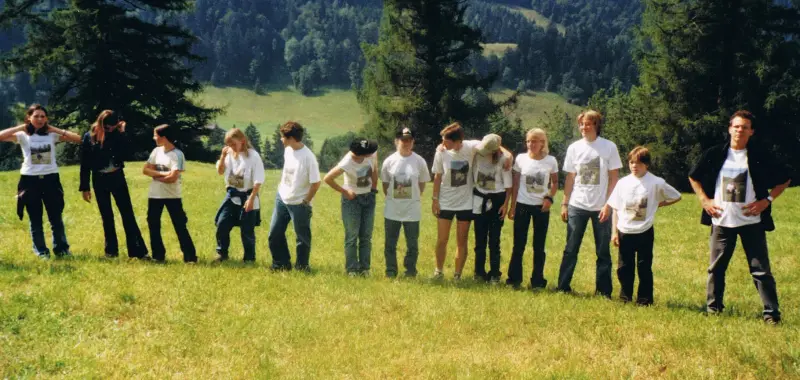 Eine Gruppe von Menschen, die in einem Feld stehen, mit einigen tragenden Kappen. – Jugend und Hund Lager 2001 in Eigenthal