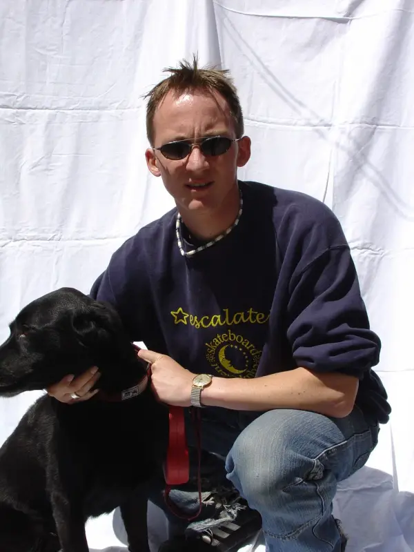 Ein Mann sitzt auf einer weissen Oberfläche mit einem Hund. – Jugend und Hund Lager 2003 in Lenzerheide