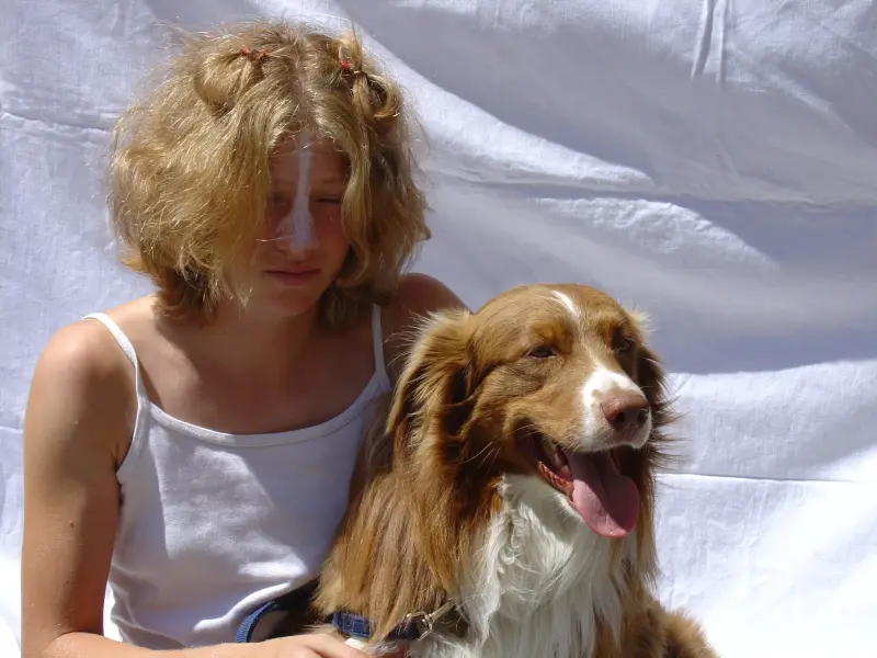 Eine Frau, die neben einem Hund auf einer weissen Decke sitzt. – Jugend und Hund Lager 2003 in Lenzerheide