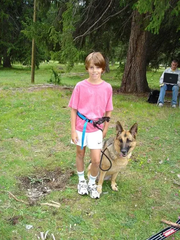 Ein junges Mädchen in einem rosa Hemd und weissen Shorts steht neben einem Hund. – Jugend und Hund Lager 2004 in Lenzerheide