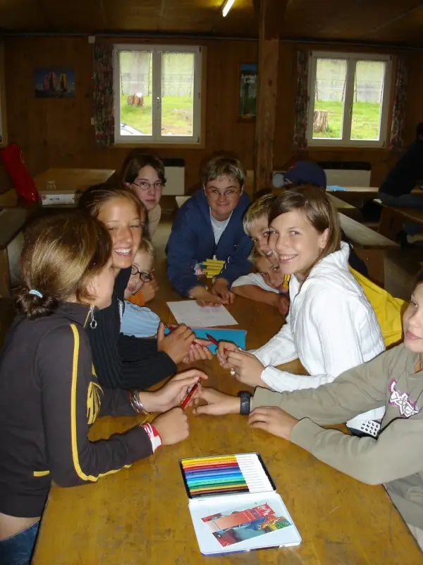 Eine Gruppe von Menschen, die um einen Tisch sitzen. – Jugend und Hund Lager 2004 in Lenzerheide