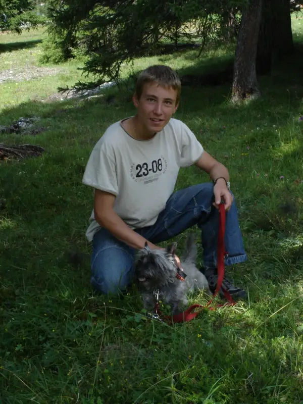Ein Junge sitzt im Gras mit einem Hund. – Jugend und Hund Lager 2004 in Lenzerheide
