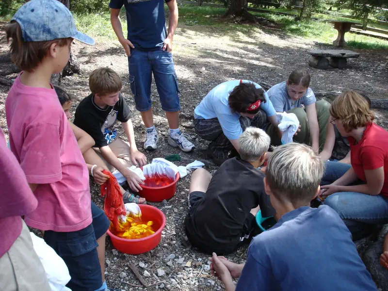 Eine Gruppe von Kindern um eine Feuerstelle versammelt. – Jugend und Hund Lager 2004 in Lenzerheide
