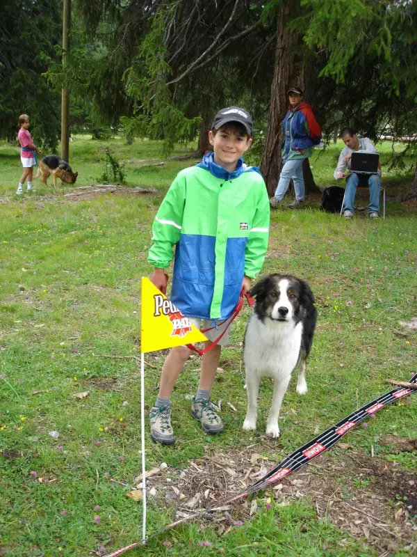 Ein kleiner Junge hält einen Stock und einen Hund. – Jugend und Hund Lager 2004 in Lenzerheide