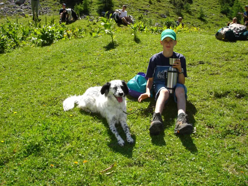 Ein Junge sitzt auf einem Hügel mit einem Hund. – Jugend und Hund Lager 2004 in Lenzerheide