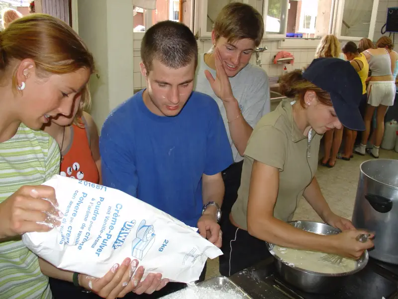Eine Gruppe von Menschen in einer Küche, die Essen zubereiten. – Jugend und Hund Lager 2004 in Lenzerheide