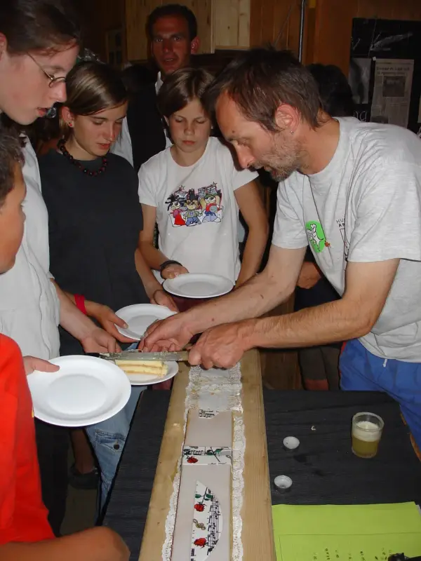 Eine Gruppe von Menschen, die um einen Tisch stehen. – Jugend und Hund Lager 2004 in Lenzerheide