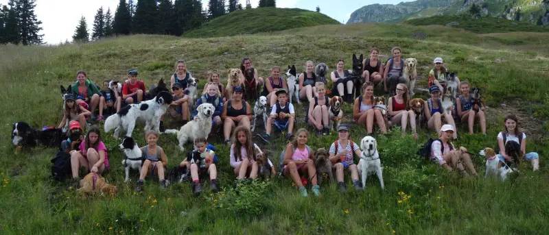 Eine Gruppe von Menschen, die mit ihren Hunden im Gras sitzen. – Jugend und Hund Lager 2015 in Segnas