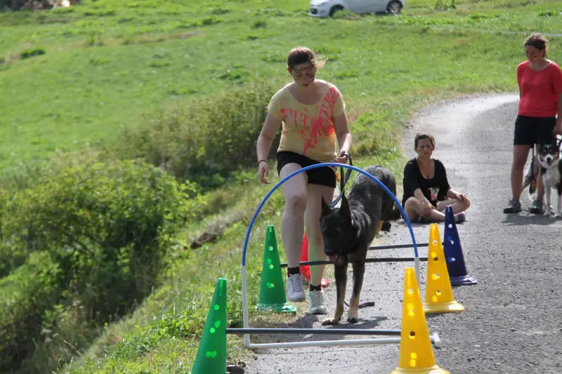 Eine Frau, die mit einem Hund an der Leine vor einer Gruppe von Menschen läuft. – Jugend und Hund Lager 2015 in Segnas