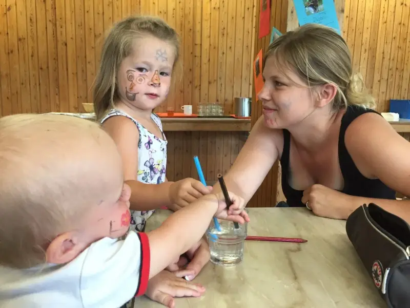Eine Frau und zwei Kinder, die an einem Tisch sitzen. – Jugend und Hund Lager 2015 in Segnas