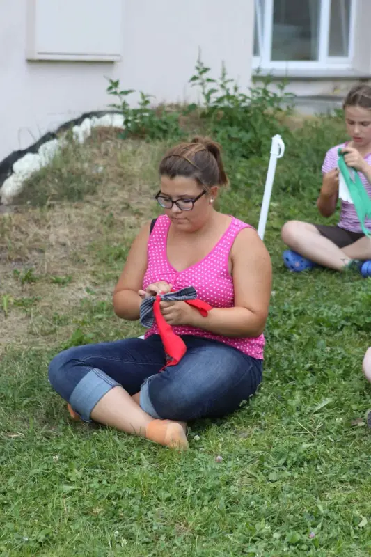 Zwei Mädchen sitzen auf dem Gras vor einem Haus. – Jugend und Hund Lager 2015 in Segnas