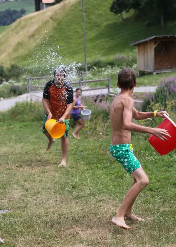 Zwei Jungen spielen mit Wasser in einem Feld. – Jugend und Hund Lager 2015 in Segnas
