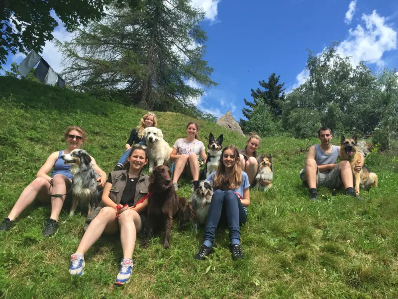 Eine Gruppe von Menschen, die auf einem Hügel mit einem Hund sitzen. – Jugend und Hund Lager 2016 in Segnas
