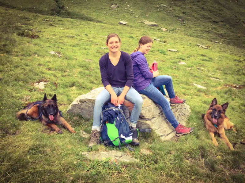 Zwei Frauen sitzen auf einem Felsen mit ihren Hunden. – Jugend und Hund Lager 2016 in Segnas