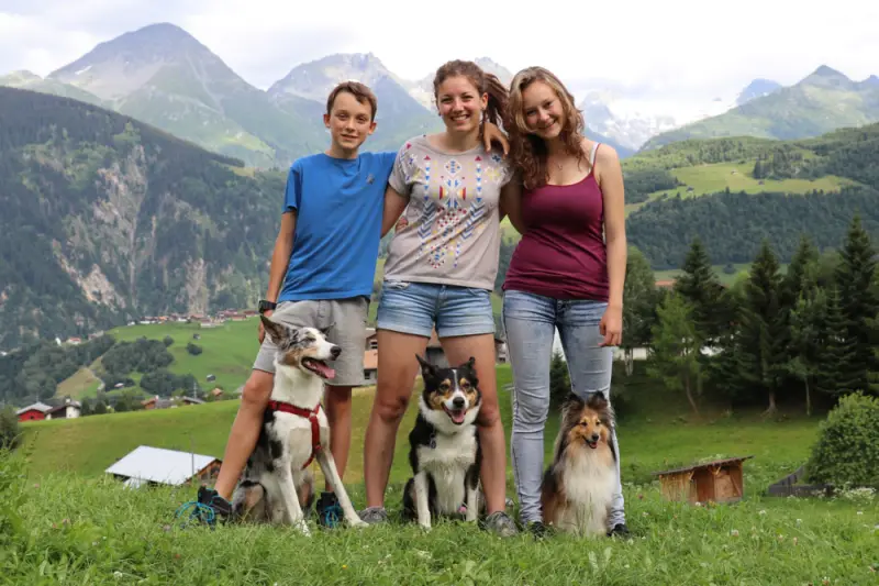 Eine Gruppe von Menschen, die auf einem Feld mit ihren Hunden stehen. – Jugend und Hund Lager 2016 in Segnas