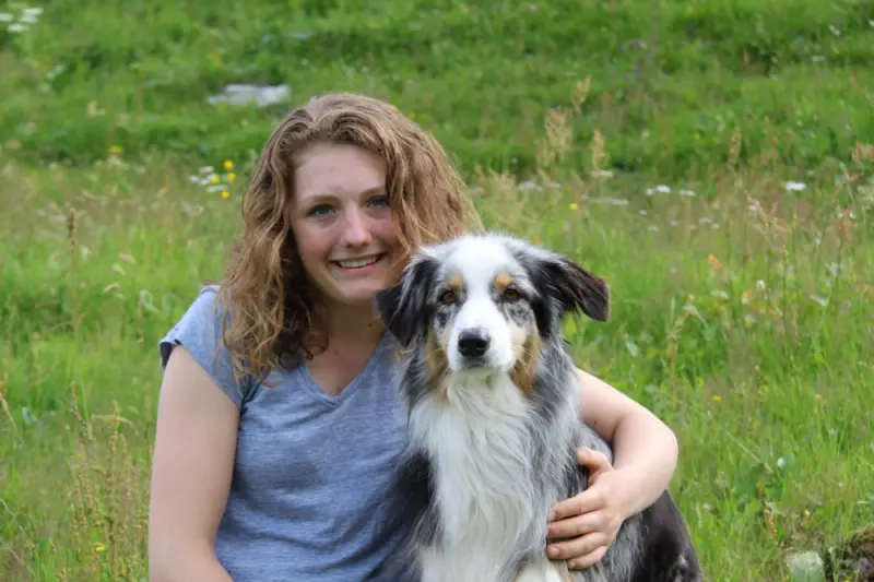 Eine Frau, die auf einem Feld mit einem Hund sitzt. – Jugend und Hund Lager 2016 in Segnas