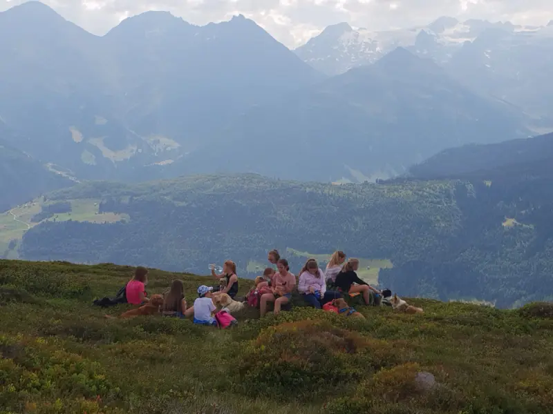 Eine Gruppe von Menschen, die auf einem Hügel sitzen. – Jugend und Hund Lager 2018 in Segnas
