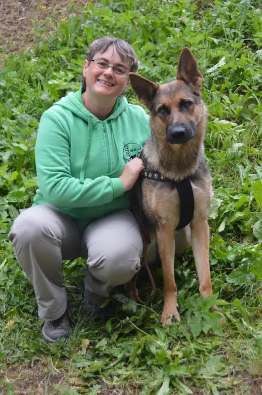 Eine Frau kniet mit einem Hund auf einem Feld nieder. – Jugend und Hund Lager 2018 in Segnas