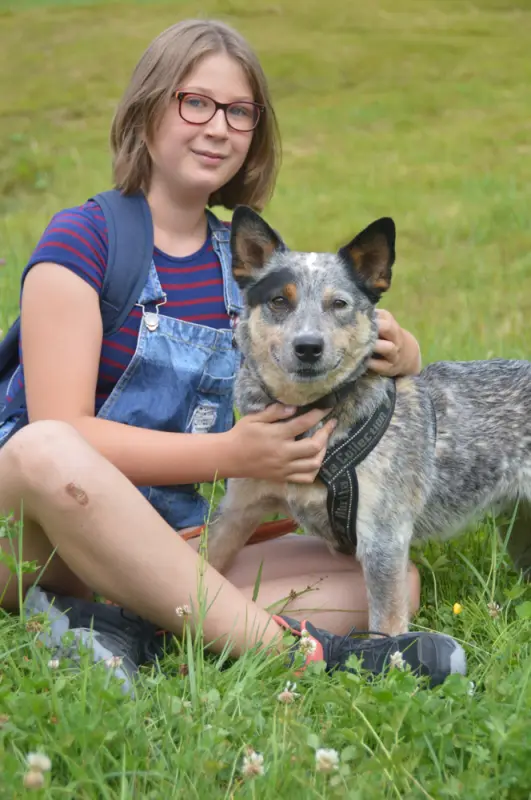 Ein Mädchen sitzt im Gras mit einem Hund. – Jugend und Hund Lager 2018 in Segnas