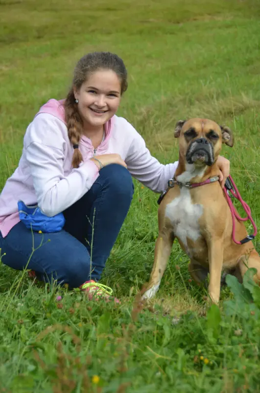 Ein Mädchen kniet mit einem Hund auf einem Feld nieder. – Jugend und Hund Lager 2018 in Segnas