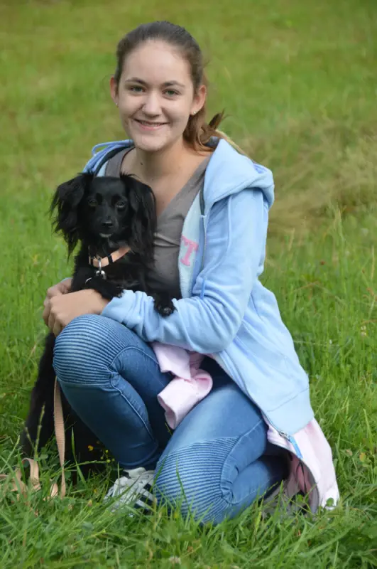 Ein Mädchen sitzt im Gras mit einem Hund. – Jugend und Hund Lager 2018 in Segnas