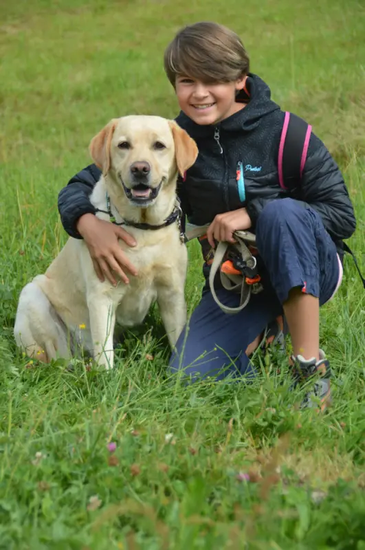 Ein junger Junge kniet mit einem Hund nieder. – Jugend und Hund Lager 2018 in Segnas