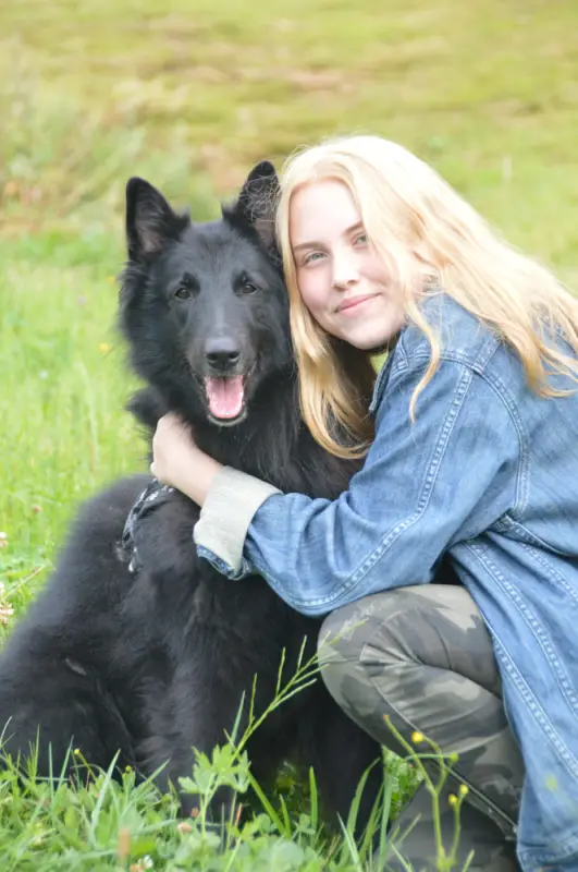 Eine Frau kniet mit einem Hund auf einem Feld nieder. – Jugend und Hund Lager 2018 in Segnas