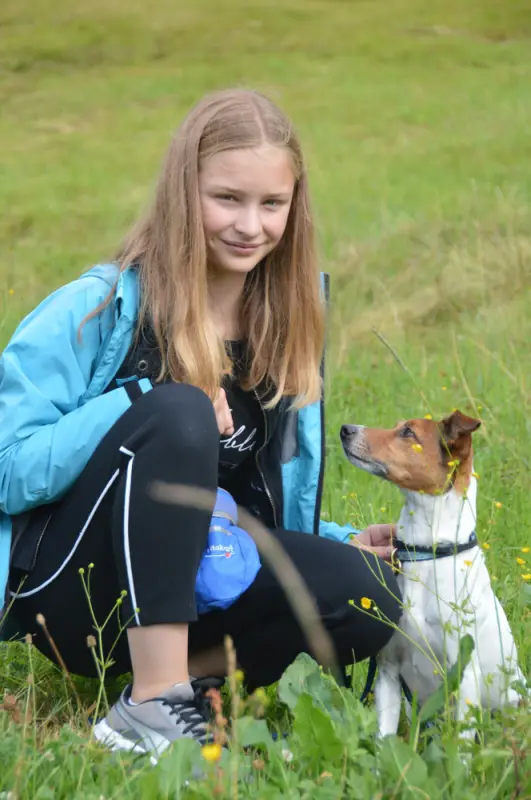 Ein Mädchen sitzt im Gras mit einem Hund. – Jugend und Hund Lager 2018 in Segnas