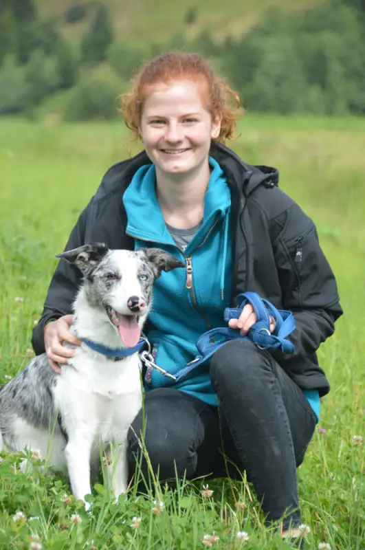 Eine Frau, die auf einem Feld mit einem Hund sitzt. – Jugend und Hund Lager 2018 in Segnas
