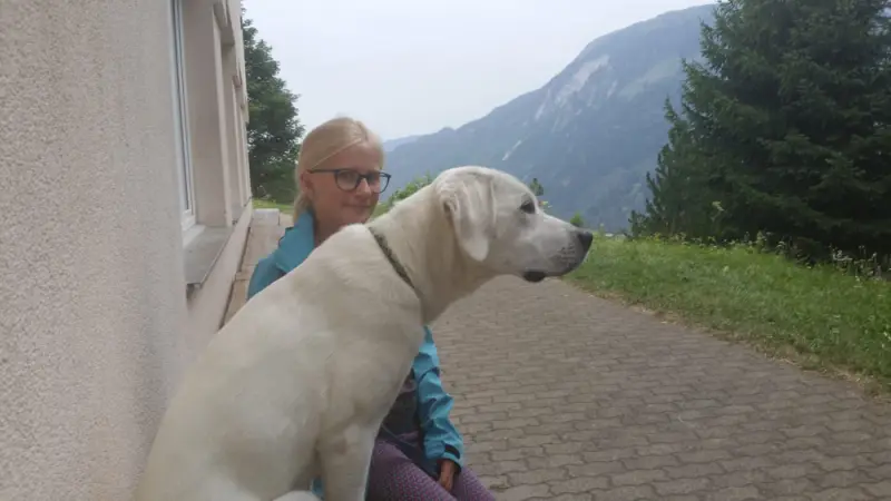 Eine Frau, die auf einer Bank mit einem Hund sitzt. – Jugend und Hund Lager 2019 in Segnas