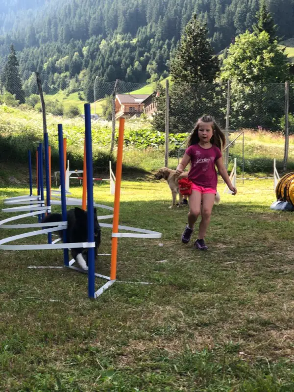 Ein Mädchen läuft durch ein Feld mit einem Spielzeug. – Jugend und Hund Lager 2019 in Segnas