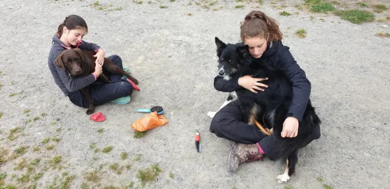 Zwei Mädchen sitzen auf dem Boden mit einem Hund. – Jugend und Hund Lager 2020 in Segnas
